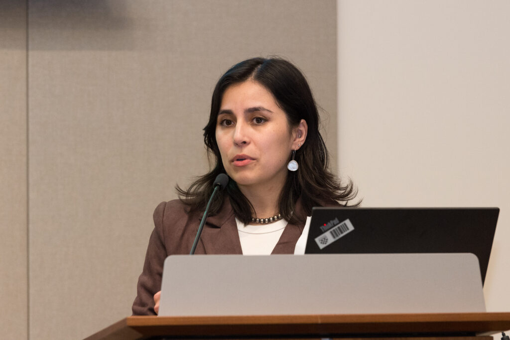 A woman standing at a podium and speaking into a microphone.