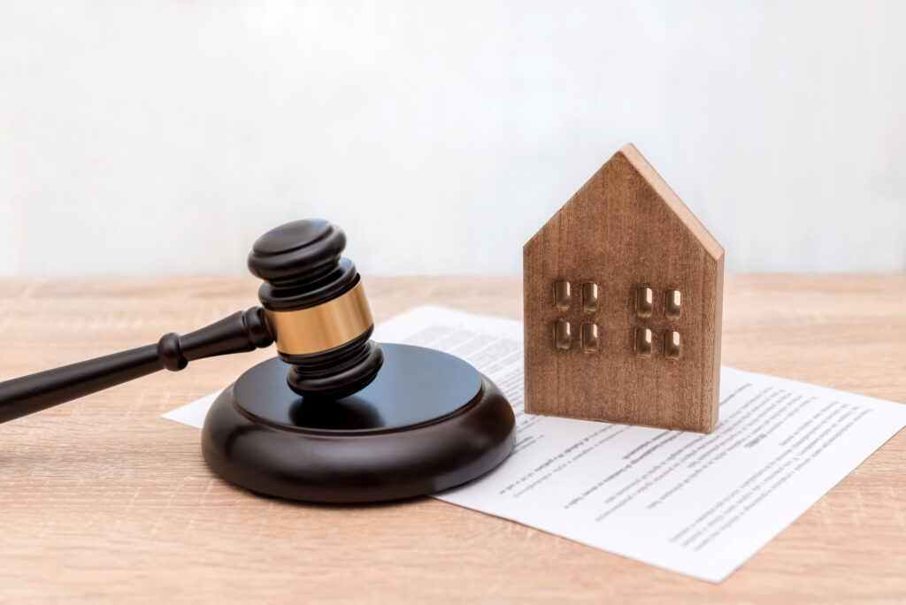 Wooden House Model with Judge's Gavel and Legal Document on Table